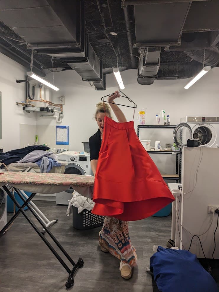 A maker pressing a custom red satin dress by hand in the studio