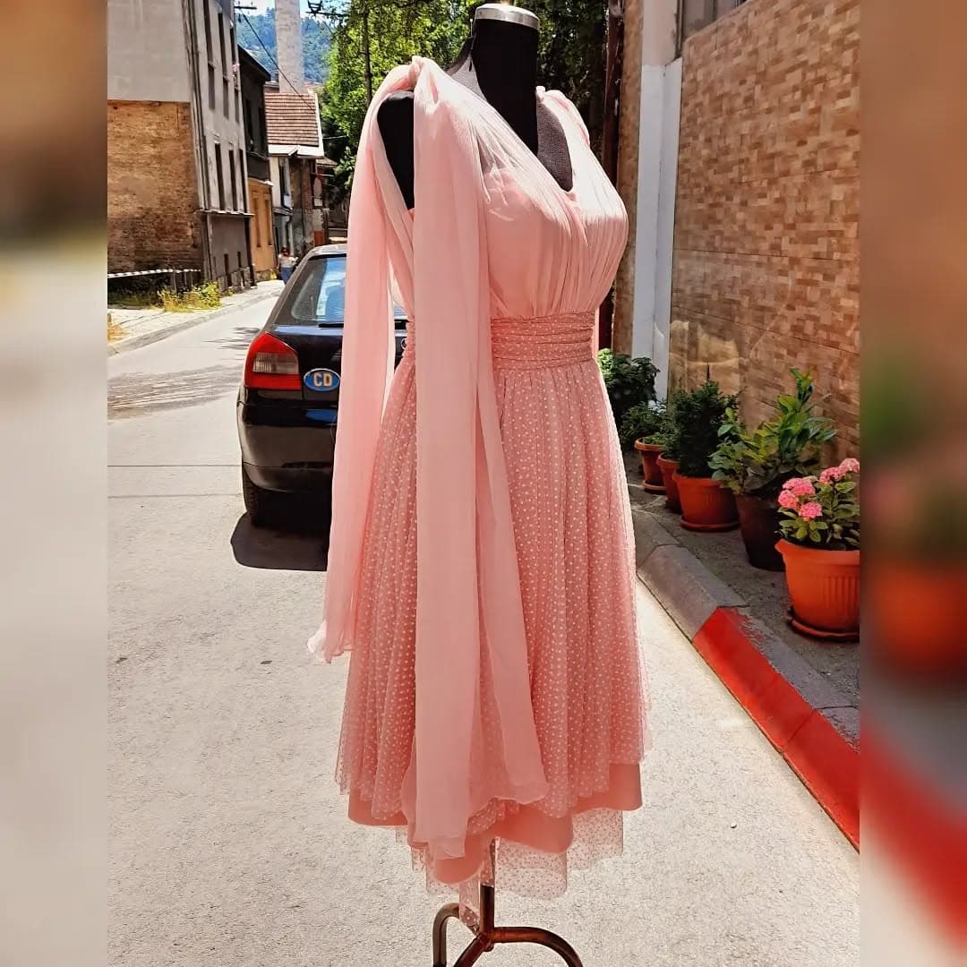 A custom blush polka-dot tulle occasion dress with bow shoulders, outside the tailor’s studio