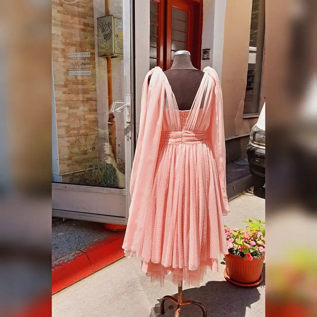 The back of a custom blush tulle occasion dress with draped bow shoulders