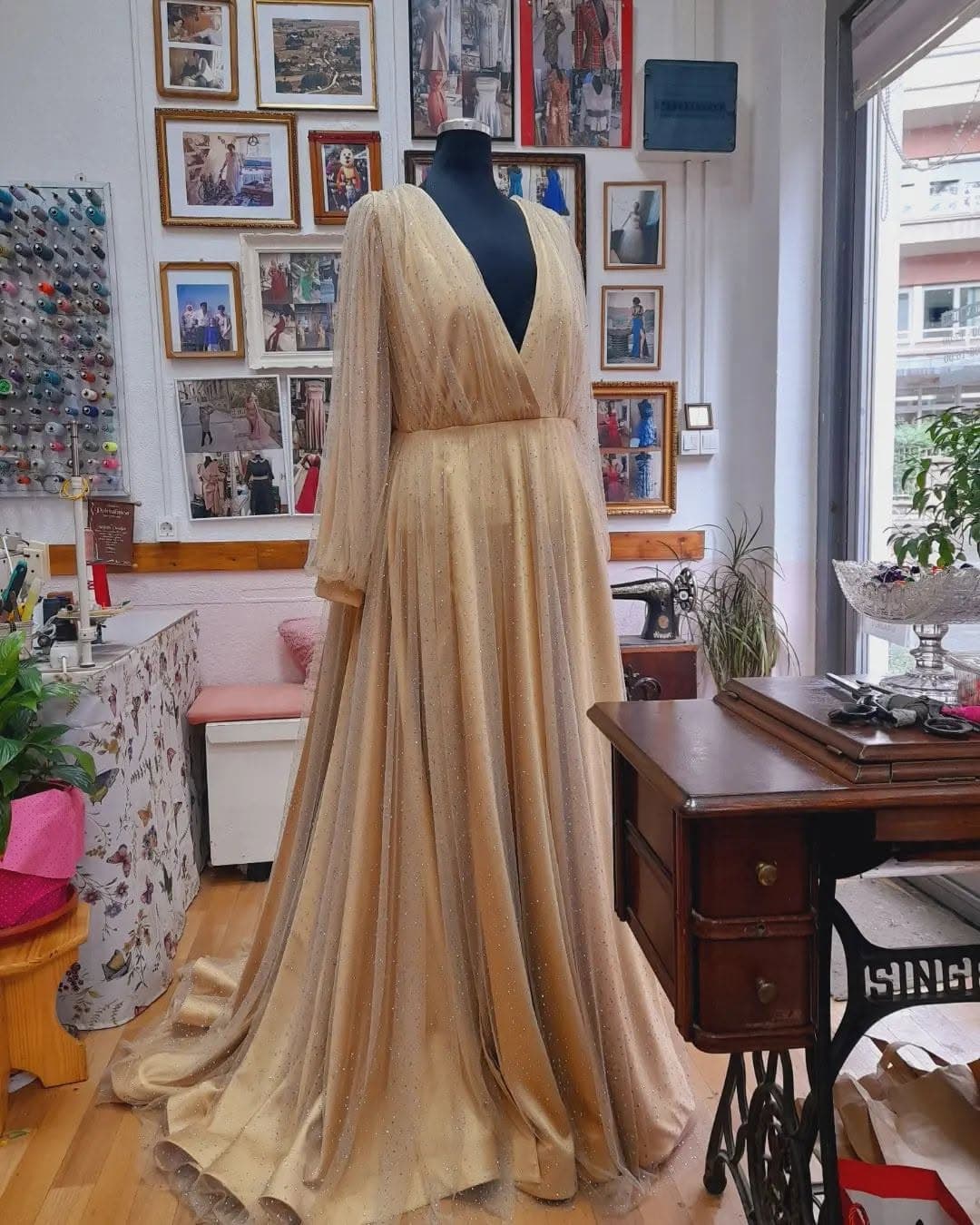 A custom gold occasion gown with sheer beaded sleeves and a full-length train, in the tailor's studio
