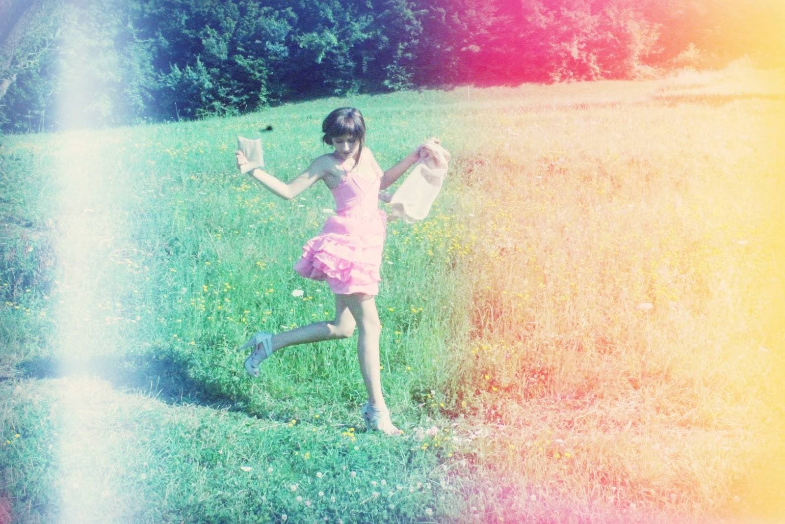 A bridesmaid dancing in a meadow in a pink ruffled custom dress