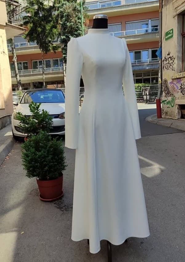 A custom ivory high-neck, long-sleeve dress with a full, comfortable skirt — made with room for the postpartum period