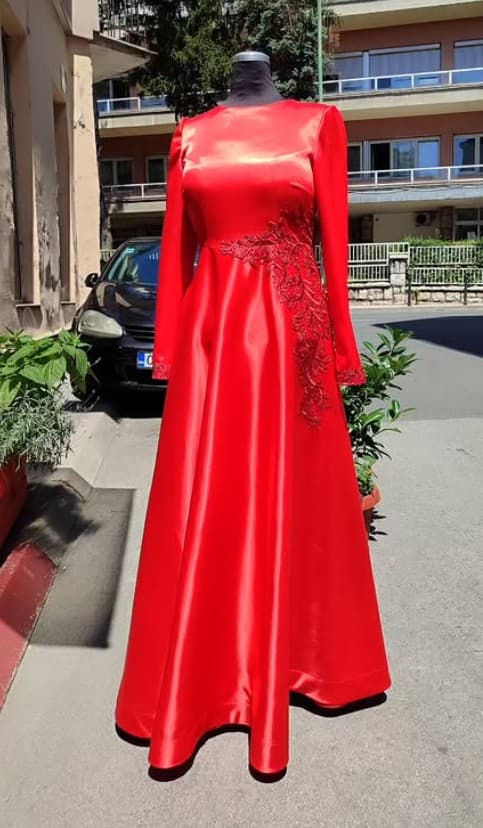 A custom red satin long-sleeve gown with beaded appliqué