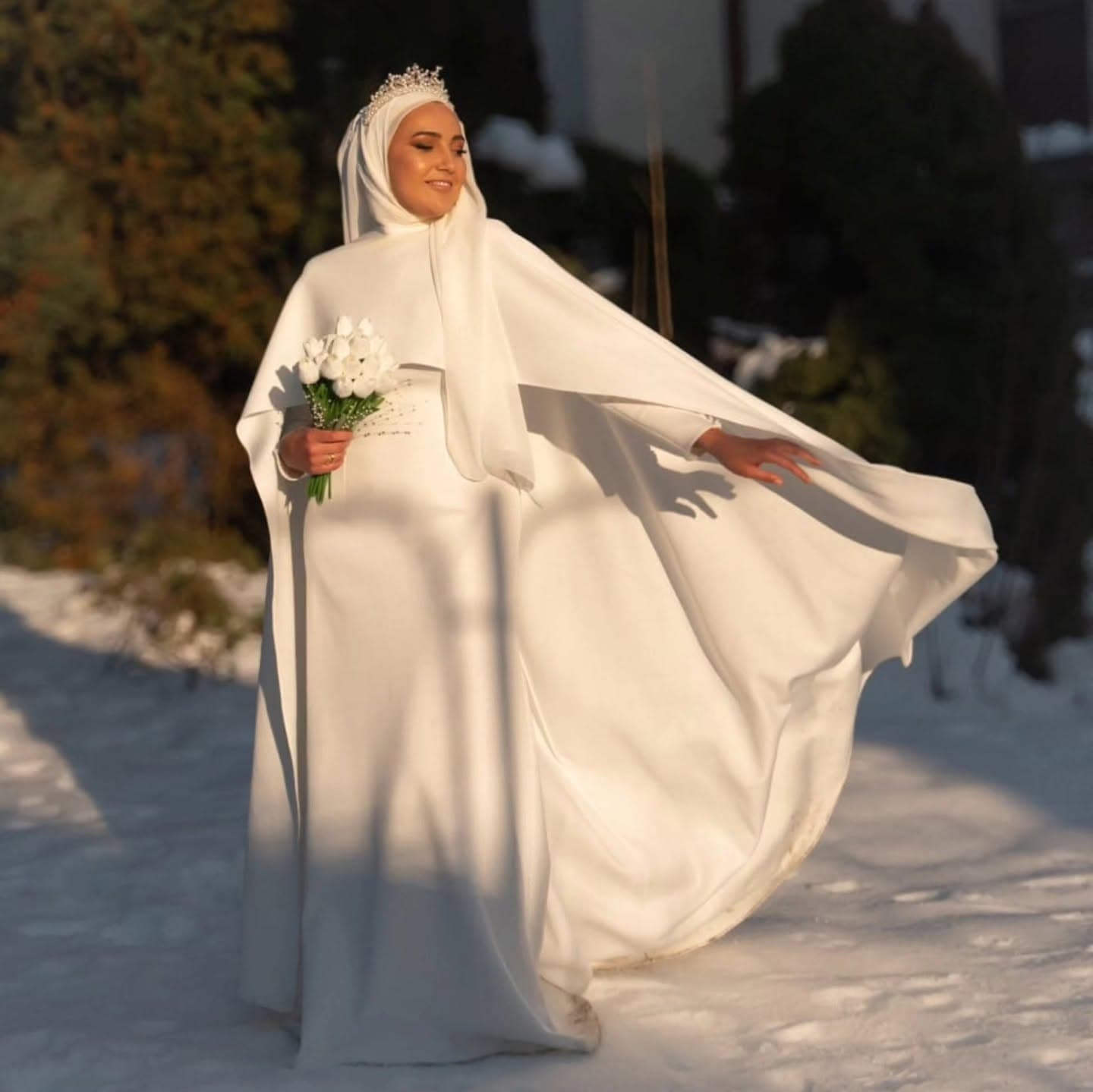 A bride in a custom modest wedding gown with long sleeves, cape and hijab styling, made to her measurements