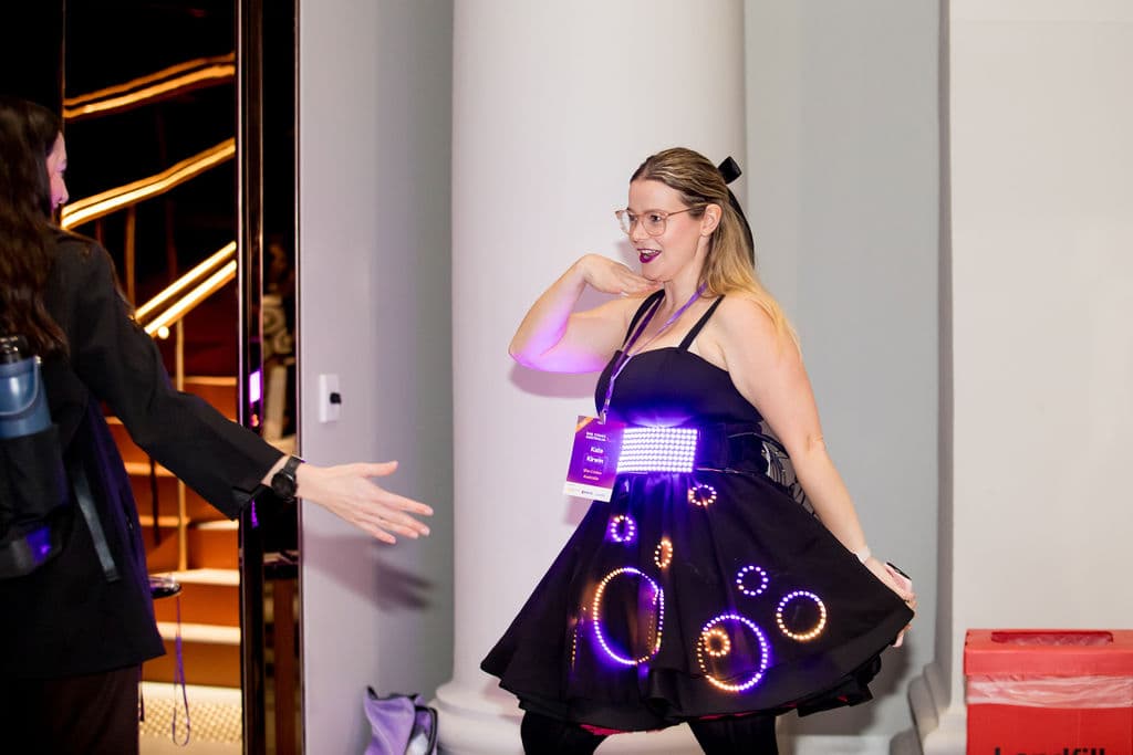 Kate mid-twirl in the lit dress, greeting someone at the showcase