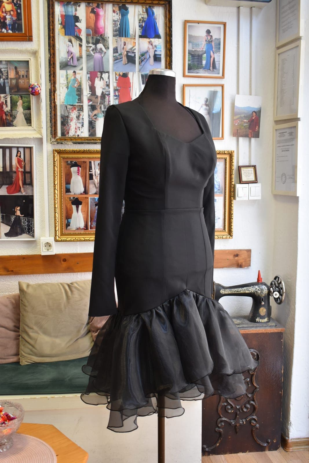 The finished black dress on a mannequin in Enisa’s Sarajevo atelier: long sleeves, sweetheart neckline, satin sash and tiered organza flounce