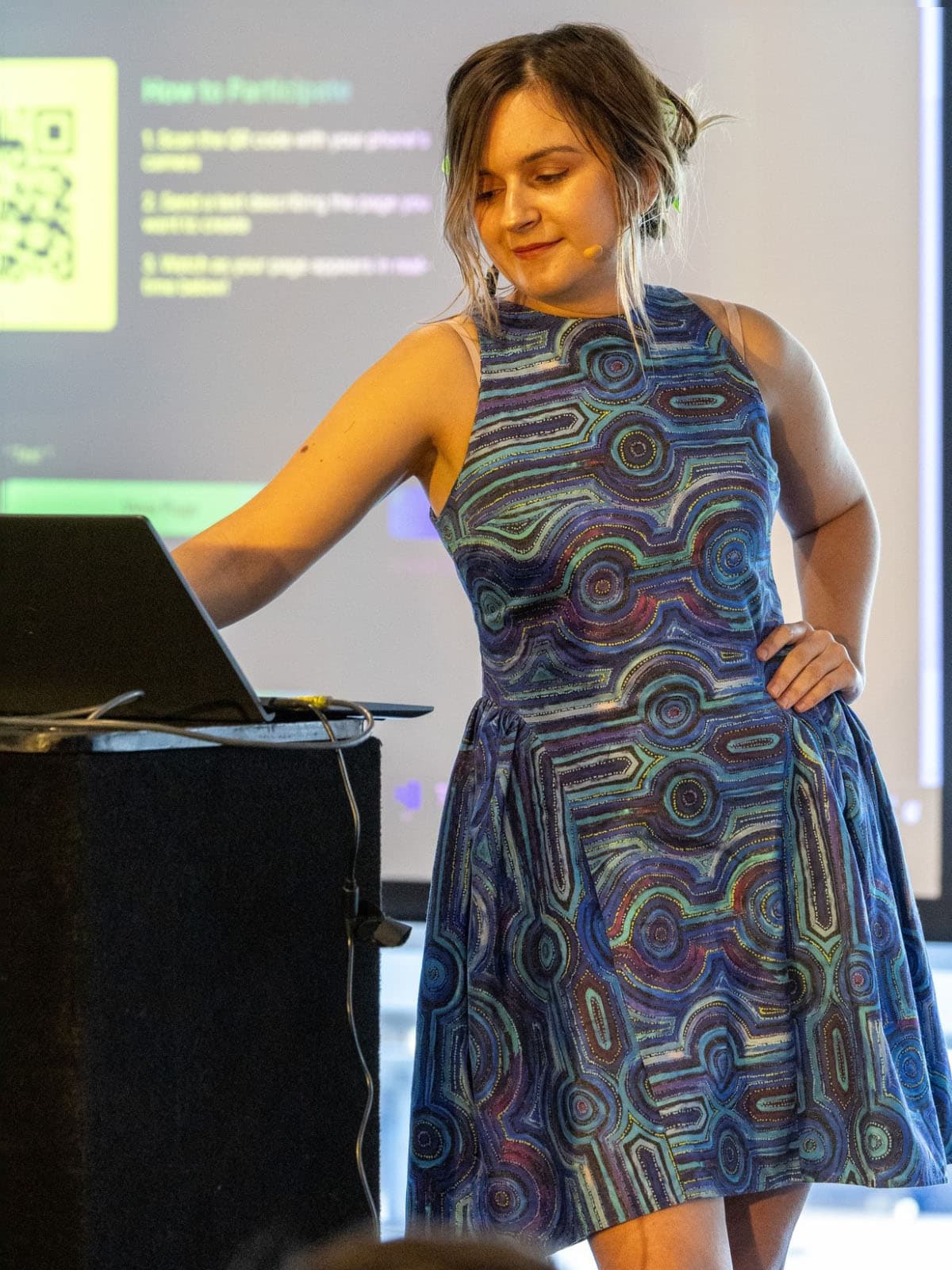 Ena on stage at a lectern wearing the finished blue print dress