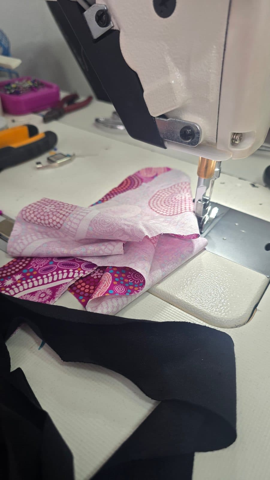 Pink and magenta print cotton under the needle of an industrial sewing machine