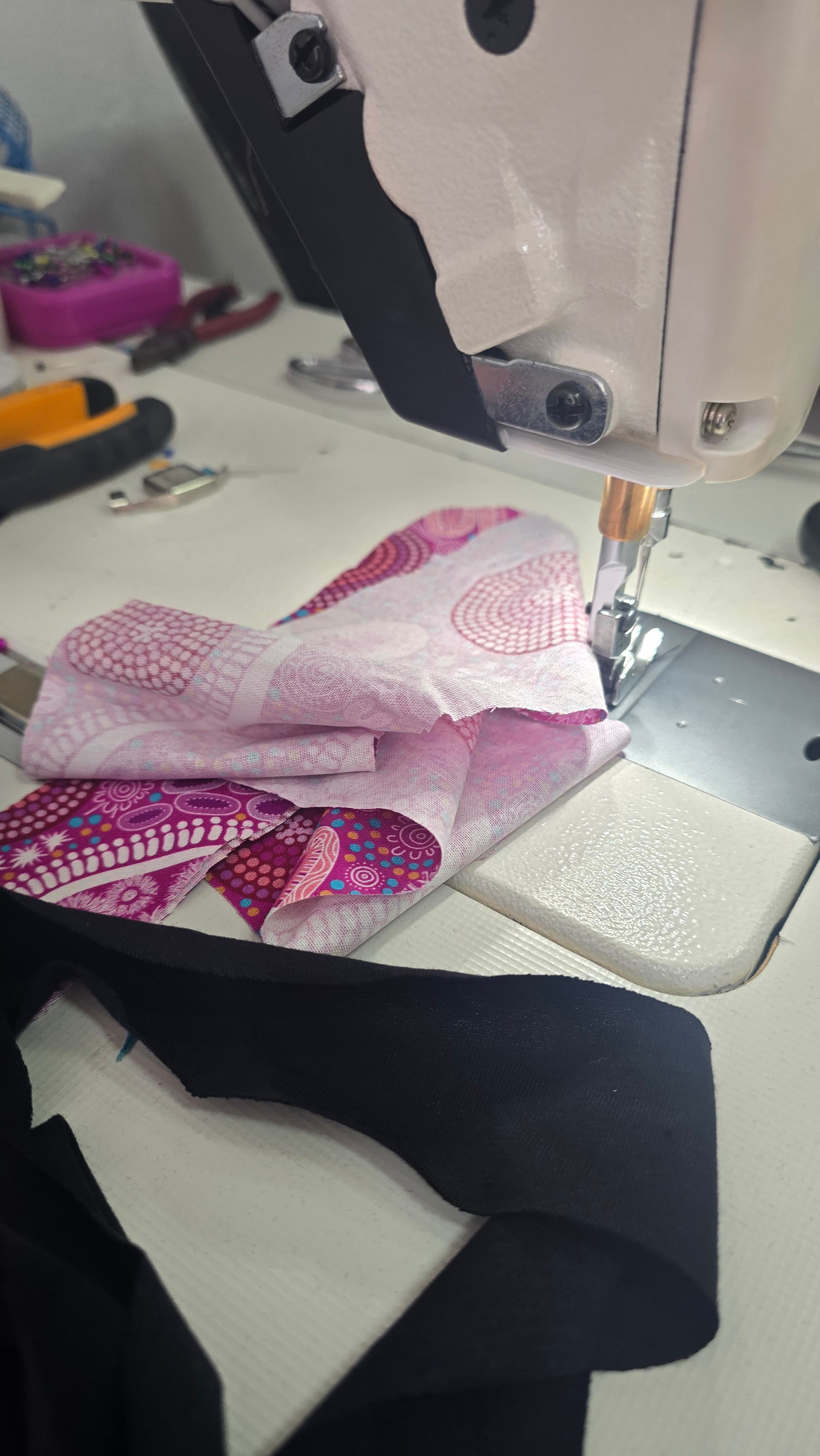 A garment under the sewing machine mid-construction — the kind of stage photo that shows an order actually exists